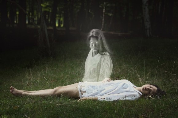 woman laying on grass and her soul sitting up