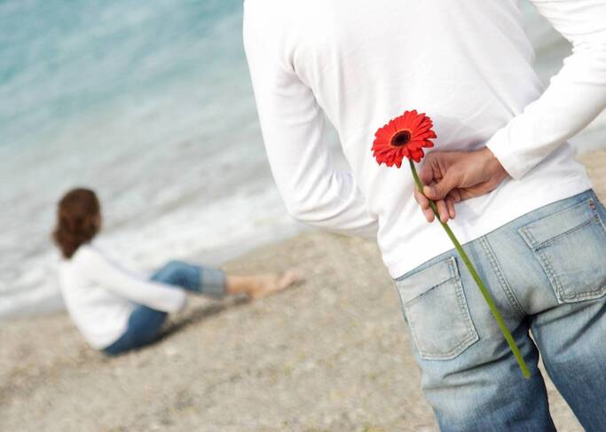 Man with flower woman sitting on beach